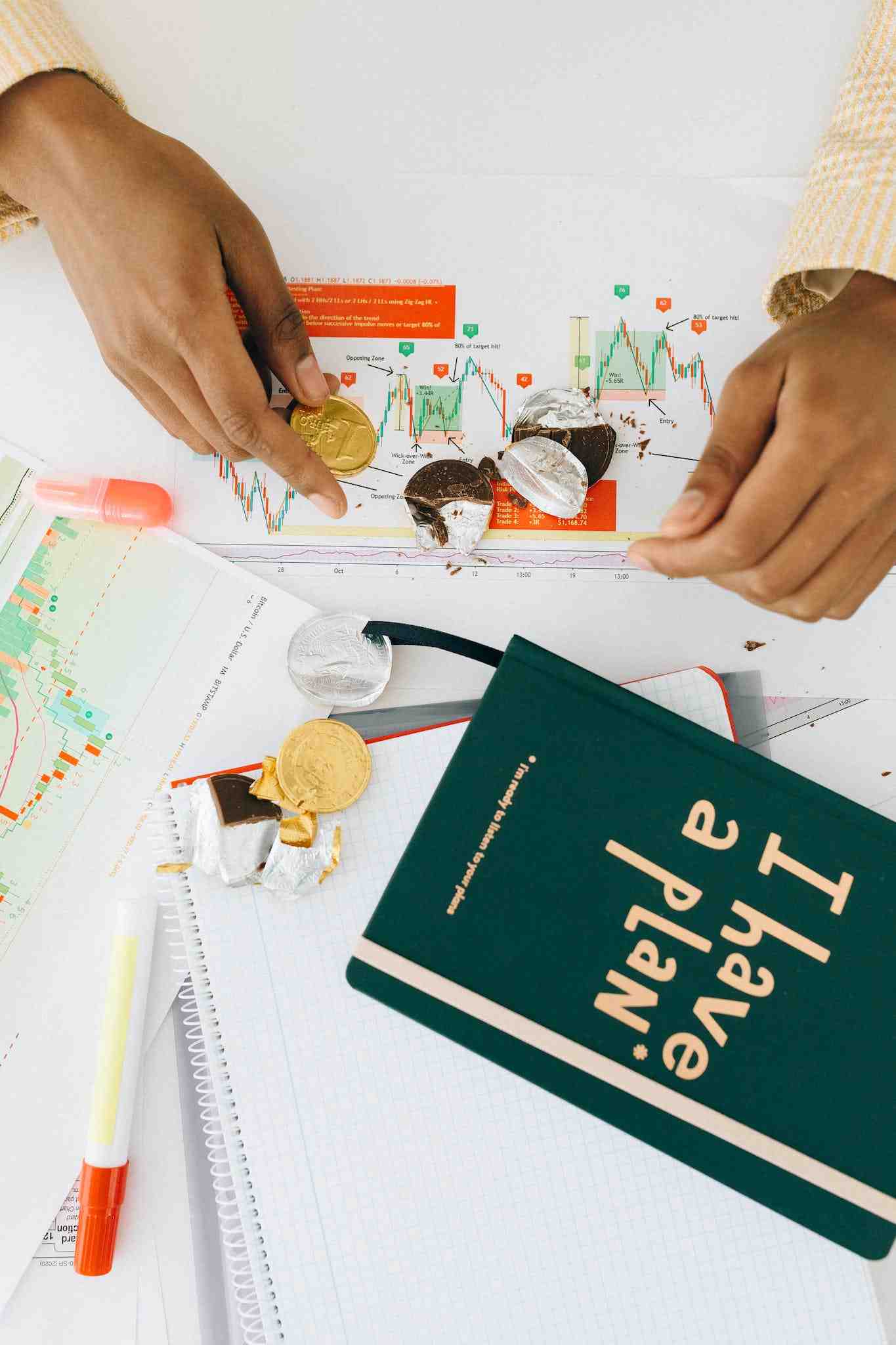 Person Holding a Gold Chocolate Coin on the Table with a Green Book
